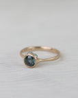 Gold ring with a blue gemstone on a white fabric background