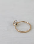 Gold ring with a diamond on a light gray background