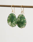 Green stone earrings on a thin rod against a light background