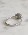 Silver ring with gemstones on a marble surface