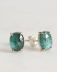 Pair of green gemstone stud earrings on a light gray background