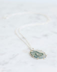 Necklace with a green and gold pendant on a white background