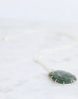 Necklace with a green stone pendant on a white background