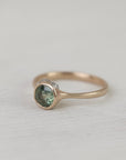 Gold ring with a green gemstone on a white fabric background