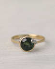 Gold ring with a green gemstone on a light fabric background
