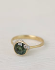 Gold ring with a green gemstone on a light fabric background
