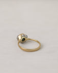 Gold ring with a central gemstone and barnacles on a light gray background