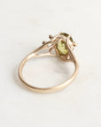 Gold ring with a green gemstone on a light gray background