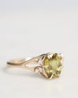 Gold ring with a green gemstone on a light gray background