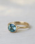 Gold ring with a blue gemstone on a light fabric background