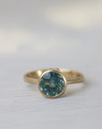 Gold ring with a blue gemstone on a white fabric background