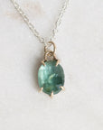 Necklace with a green gemstone pendant on a light background