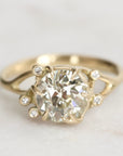 Gold ring with a large diamond and smaller diamonds on a light background