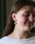 Woman wearing green earrings with a neutral background