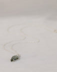 Necklace with a green stone pendant on a light gray background