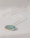Necklace with a pendant featuring a green stone and small roses on a light gray background