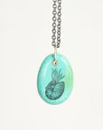 Necklace with a turquoise pendant featuring a black engraved design on a white background