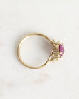 Gold ring with a purple gemstone on a light gray background