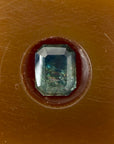 Faceted gemstone in a brown setting on a brown background