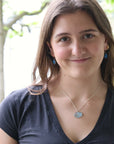 woman wearing necklace with large blue gemstone