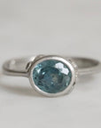 Silver ring with a blue gemstone on a light gray background