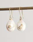 Pearl earrings with gold accents on a gray background