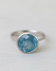 Silver ring with a blue gemstone on a light gray background