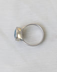 Silver ring with a blue gemstone on a light gray background
