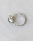 Silver ring with a blue gemstone on a light gray background