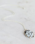 Necklace with a black and white patterned pendant on a light gray background