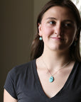 Woman wearing a necklace with a turquoise pendant indoors