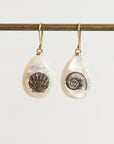 Teardrop-shaped earrings with shell designs on a white background