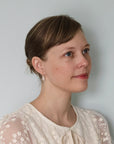 Woman wearing a white lace top against a plain background with drop herkimer quartz earrings