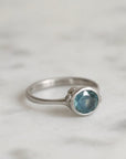 Silver ring with a blue gemstone on a light gray background