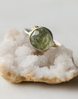 Ring with a green stone on a piece of crystal rock against a light background