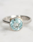 Silver ring with a blue gemstone on a light gray background
