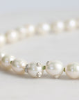 Pearl necklace with small silver accents on a light gray background
