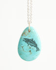 Turquoise pendant with fish design on a white background