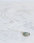 Necklace with a teardrop-shaped gemstone pendant on a marble background
