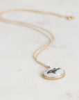 Necklace with a pendant featuring an orca on a light background