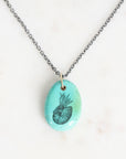 Necklace with a turquoise pendant featuring a black design on a white background
