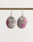 Pair of earrings with pink and gray stones on a white background