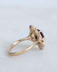 Gold ring with a red gemstone on a light gray background