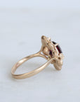 Gold ring with a red gemstone on a light gray background