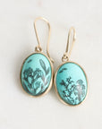 Pair of earrings with turquoise oval stones featuring black seaweed patterns on a white background
