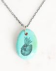 Necklace with a turquoise pendant featuring a black and white design on a white background