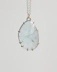 Necklace with a large teardrop-shaped green stone on a light gray background