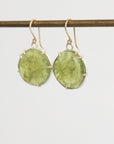 Green stone earrings on a thin rod against a light gray background