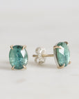 Pair of green gemstone stud earrings on a light gray background