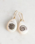 Pair of earrings with shell designs on a light background